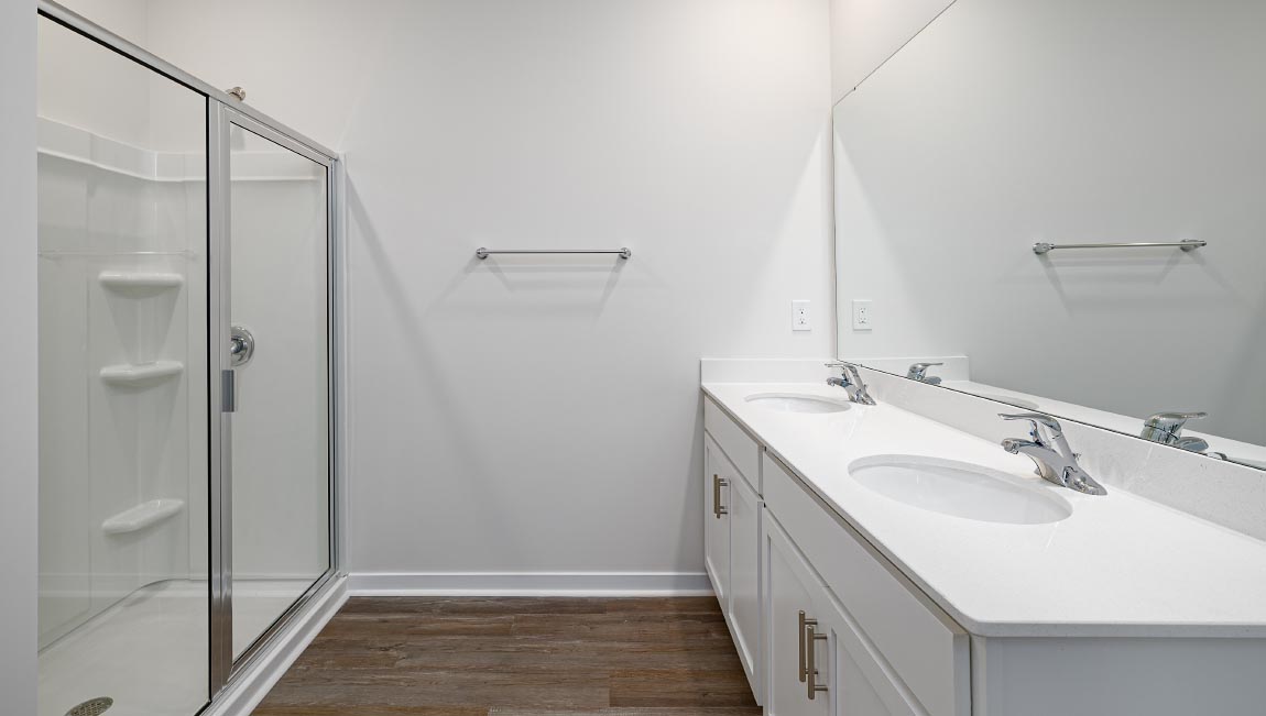 Primary bathroom with dual vanity and walk in shower with glass doors