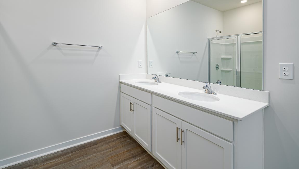 Primary bathroom with dual vanity and walk in shower with glass doors