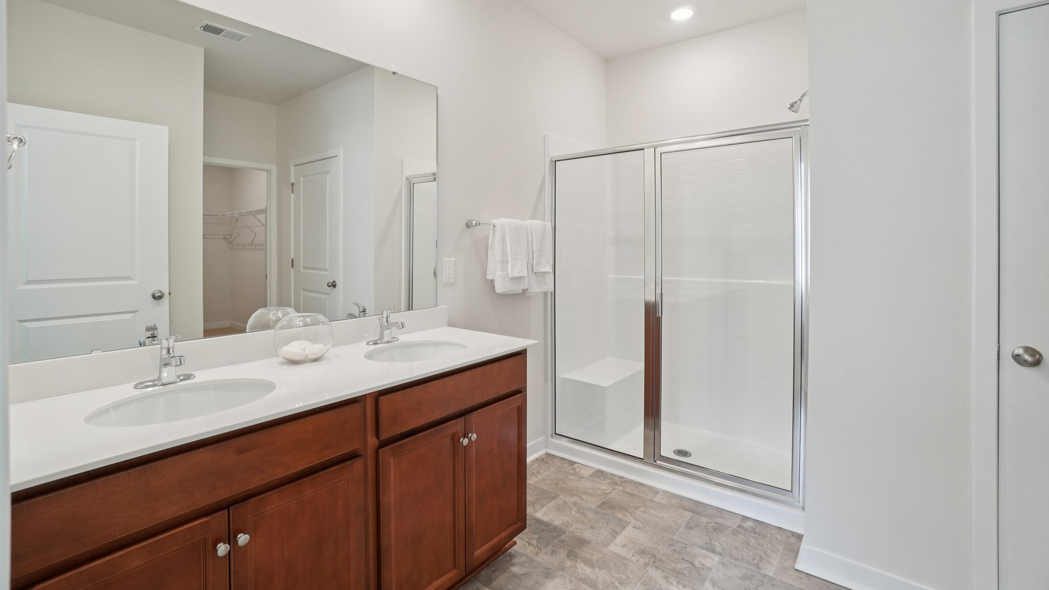 Primary bathroom with dual vanity and walk in shower with glass doors