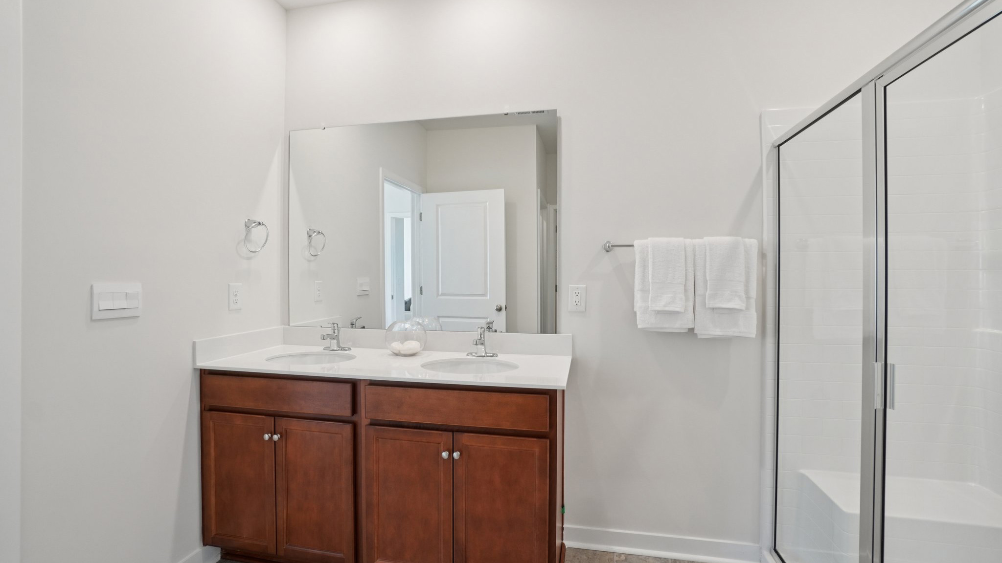 Primary bathroom with dual vanity and walk in shower with glass doors