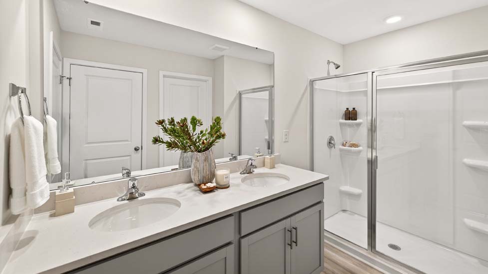 Primary bathroom with dual vanity and walk in shower with glass doors