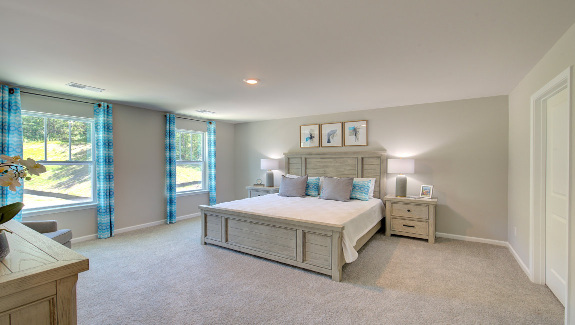 Carpeted primary bedroom with large windows