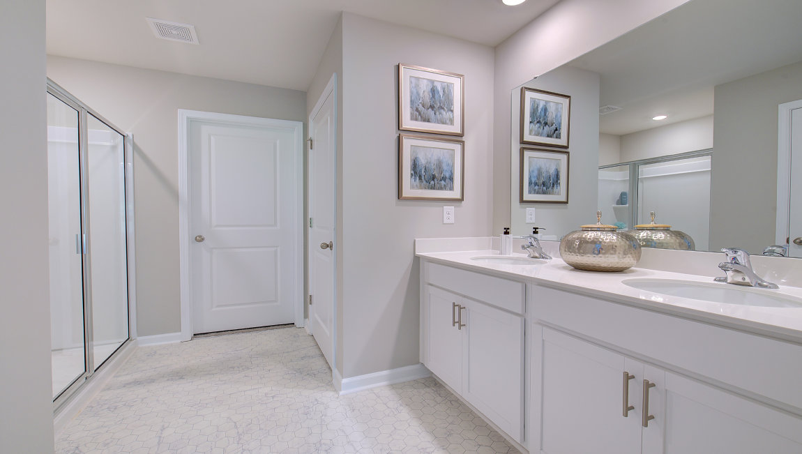Primary bathroom with dual vanity and walk in shower with glass doors