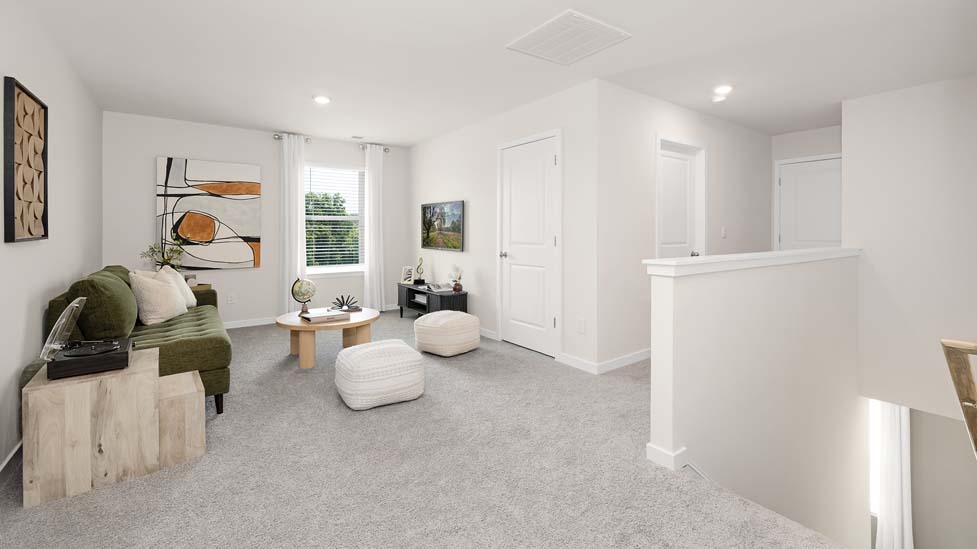 Carpeted open loft area with windows