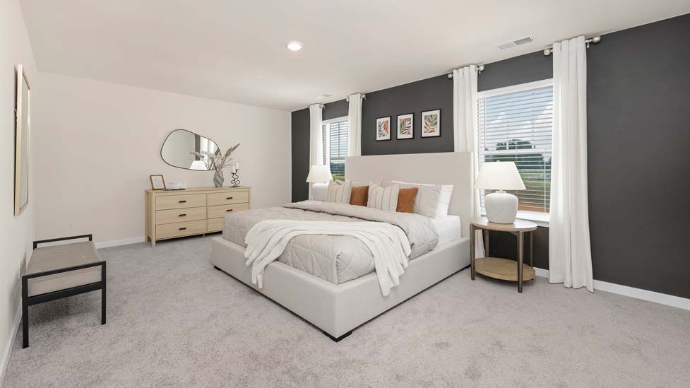Carpeted primary bedroom with large windows