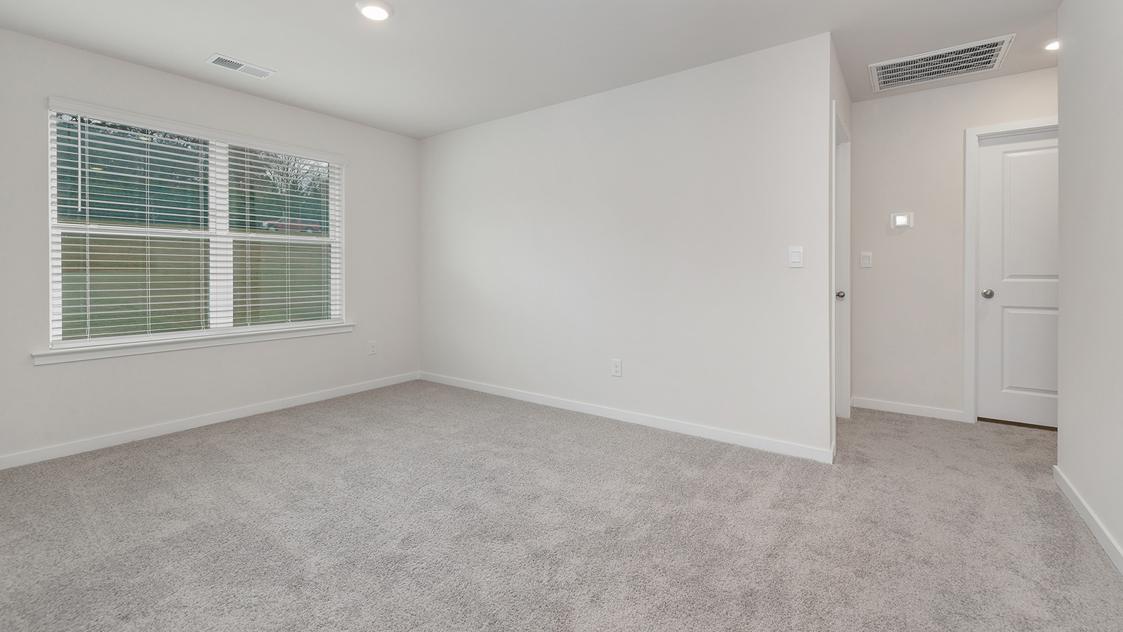 Carpeted open living area with large windows