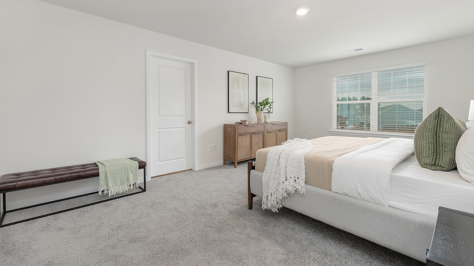 Carpeted primary bedroom with large windows