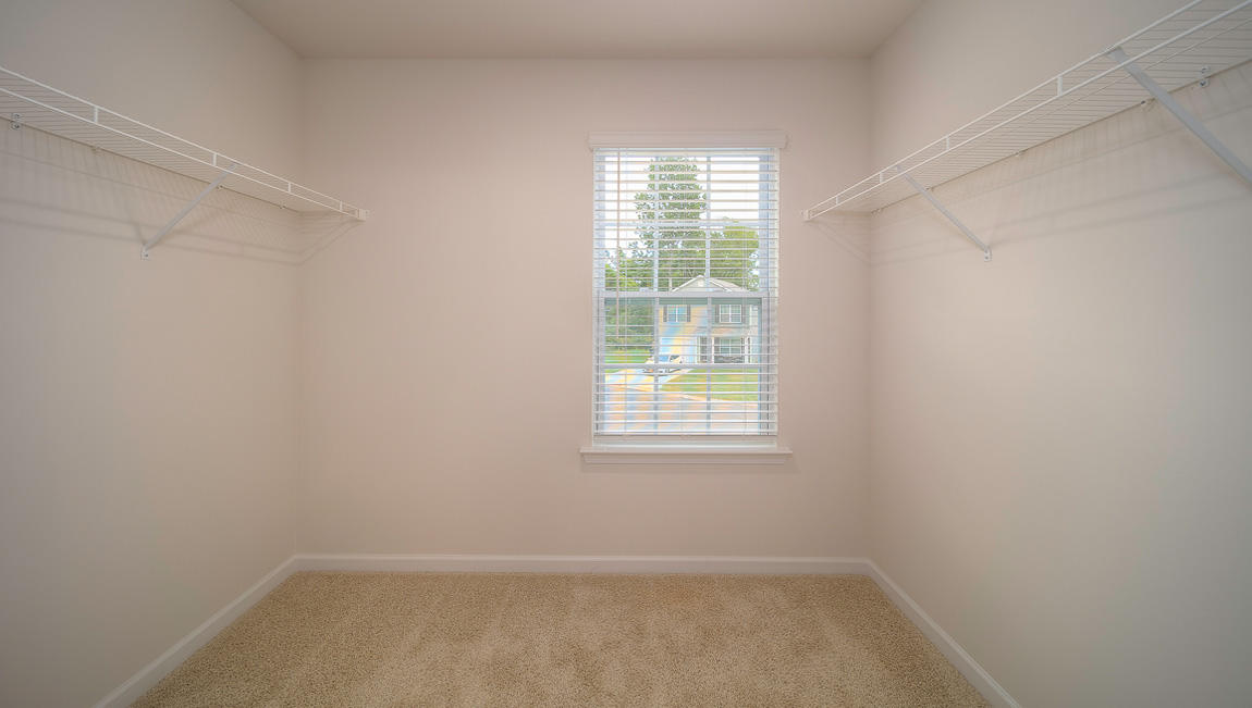 Primary bedroom walk in closet with small window