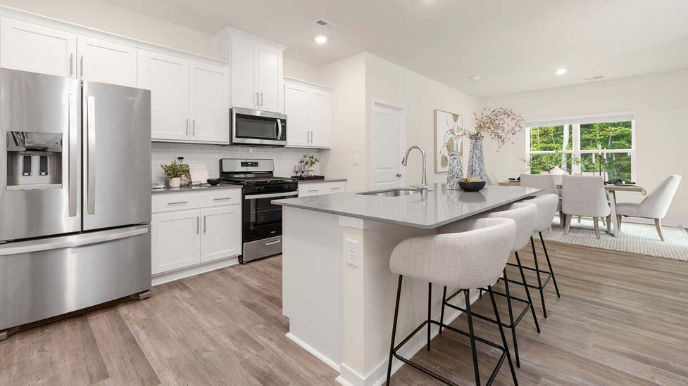 Kitchen and island with white cabinets, quarts countertops, wood floors, and stainless steel appliances
