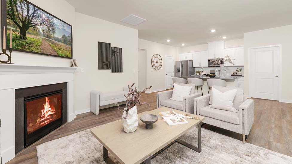 Modern open-concept living room with wood floors, and a fireplace, located beside kitchen