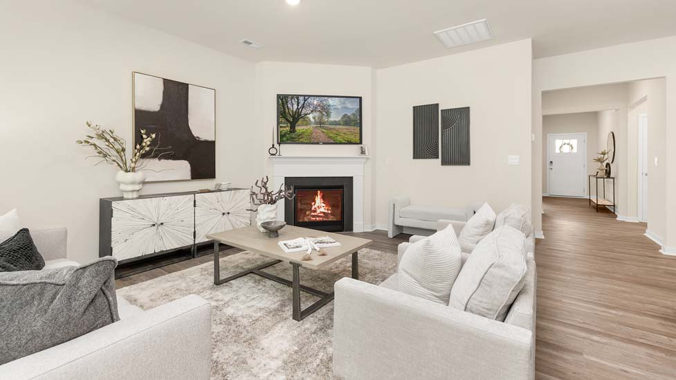 Modern open-concept living room with wood floors, and a fireplace, located beside kitchen