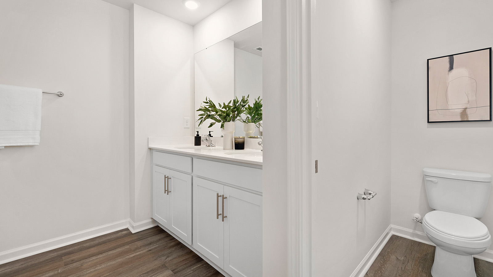 Primary bathroom with double vanity, white cabinets and standing glass door shower
