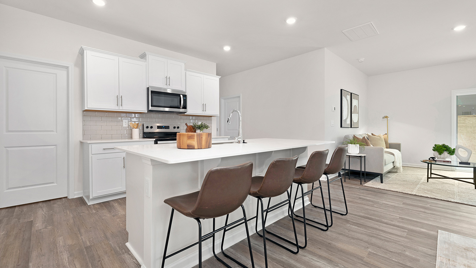 Kitchen and island with subway tile backsplash, quartz countertops, white cabinets and stainless steel appliances