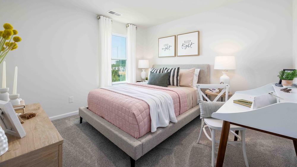 Model primary carpeted bedroom with large window