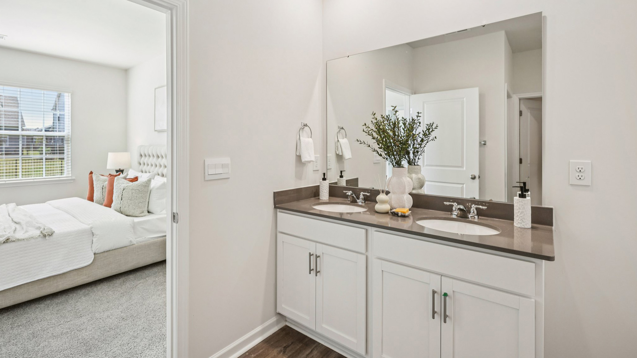 Bathroom with double vanity looking into bedroom