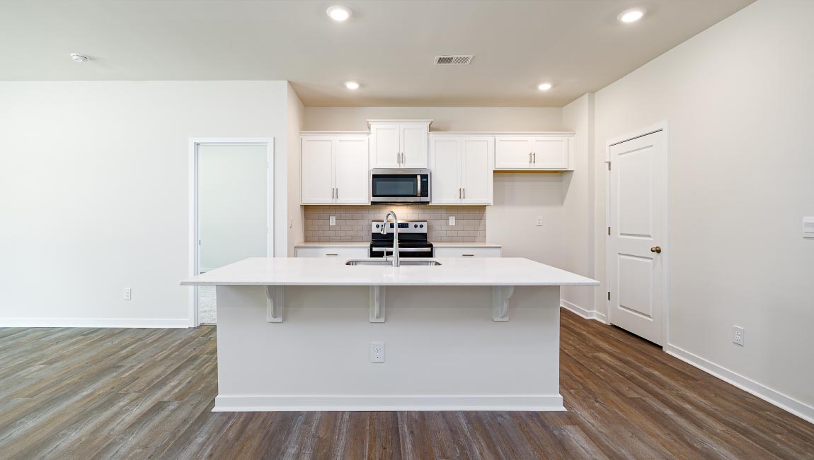 Kitchen and island with white cabinets, quarts countertops, wood floors, and stainless steel appliances