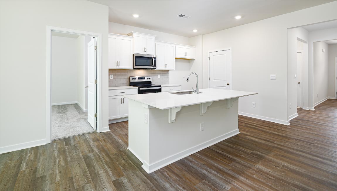 Kitchen and island with white cabinets, quarts countertops, wood floors, and stainless steel appliances