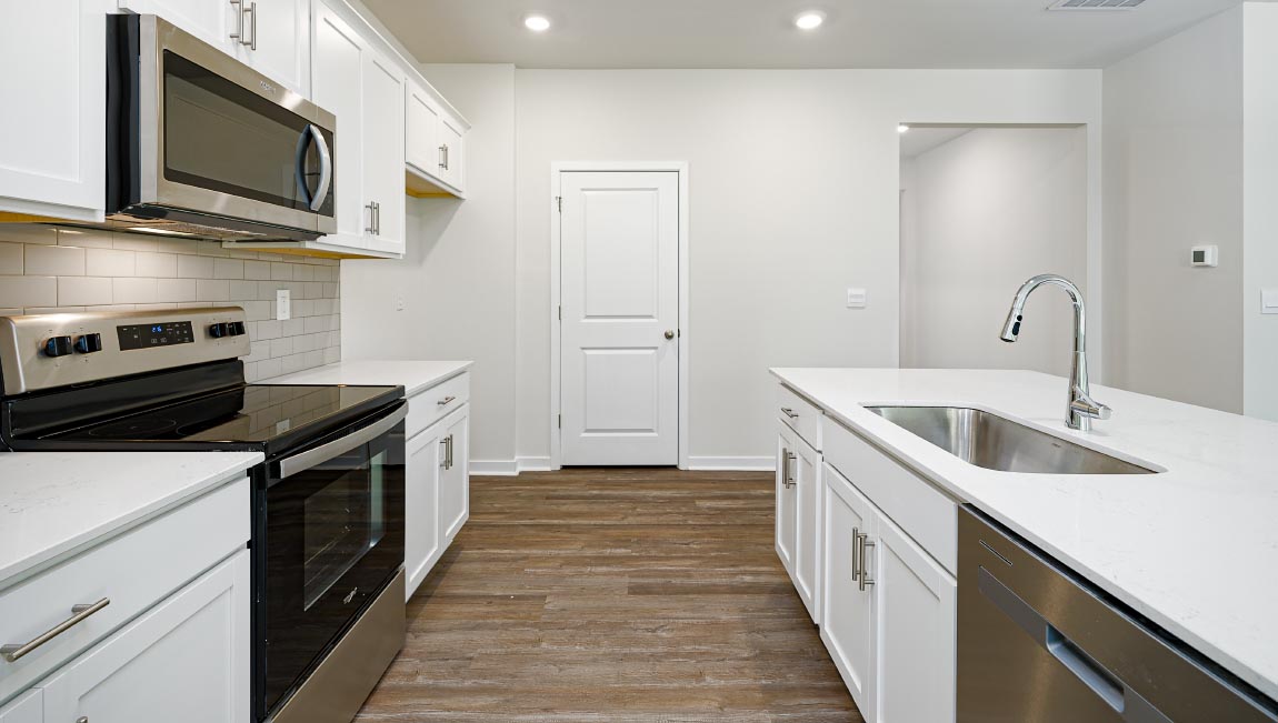 Kitchen and island with white cabinets, quarts countertops, wood floors, and stainless steel appliances
