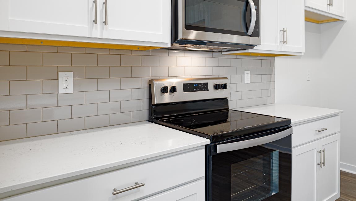 Kitchen and island with white cabinets, quarts countertops, wood floors, and stainless steel appliances