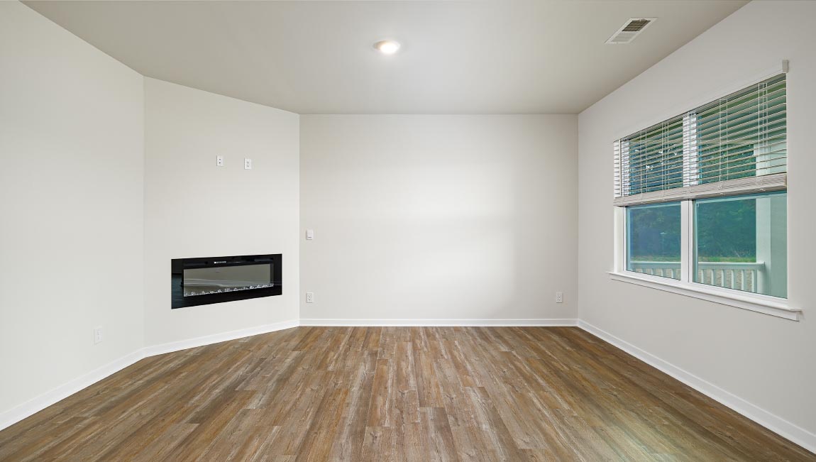 Modern open-concept living room with wood floors, and a fireplace, located beside kitchen