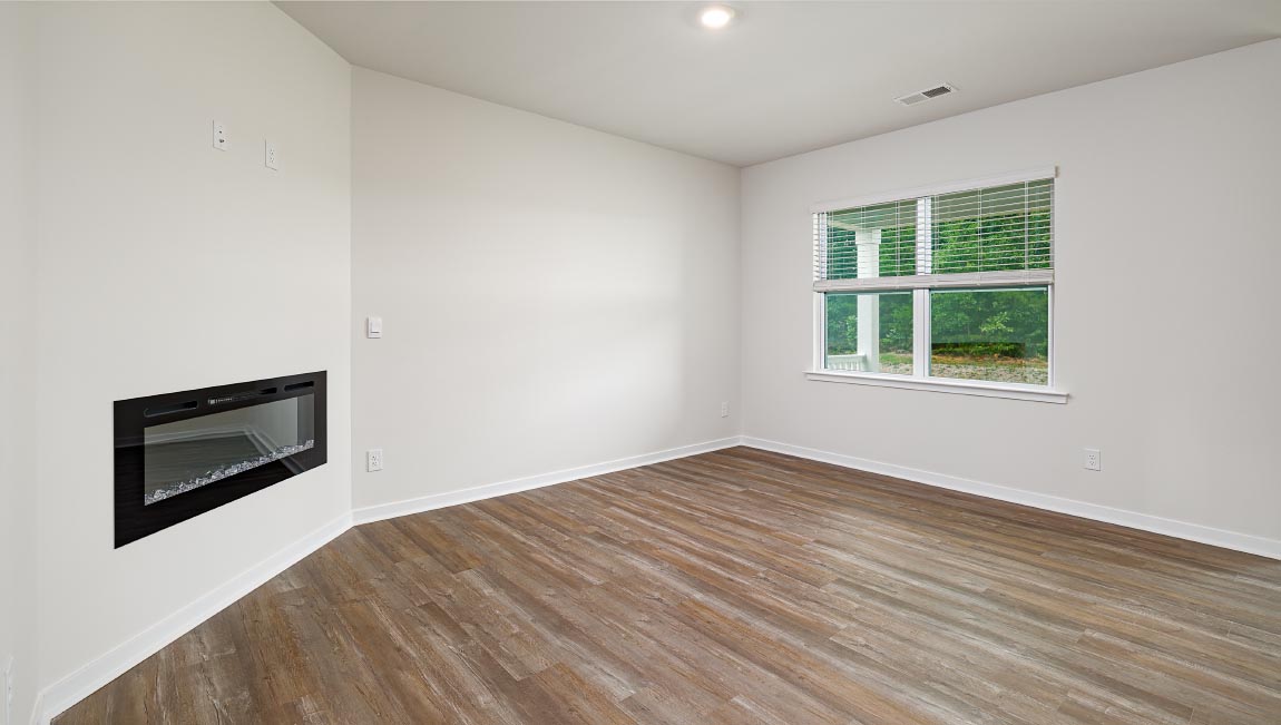 Modern open-concept living room with wood floors, and a fireplace, located beside kitchen