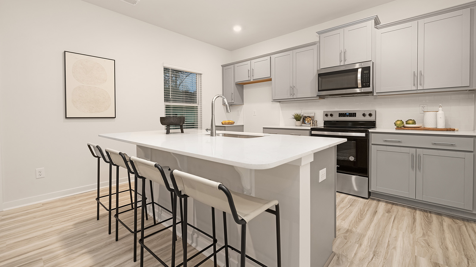 kitchen and island with white cabinets, wood floors and stainless steel appliances