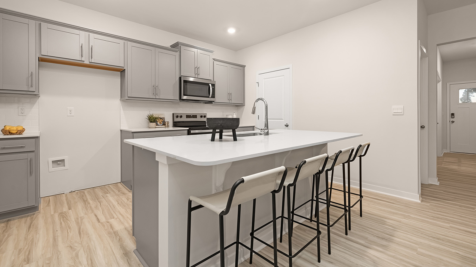 kitchen and island with white cabinets, wood floors and stainless steel appliances