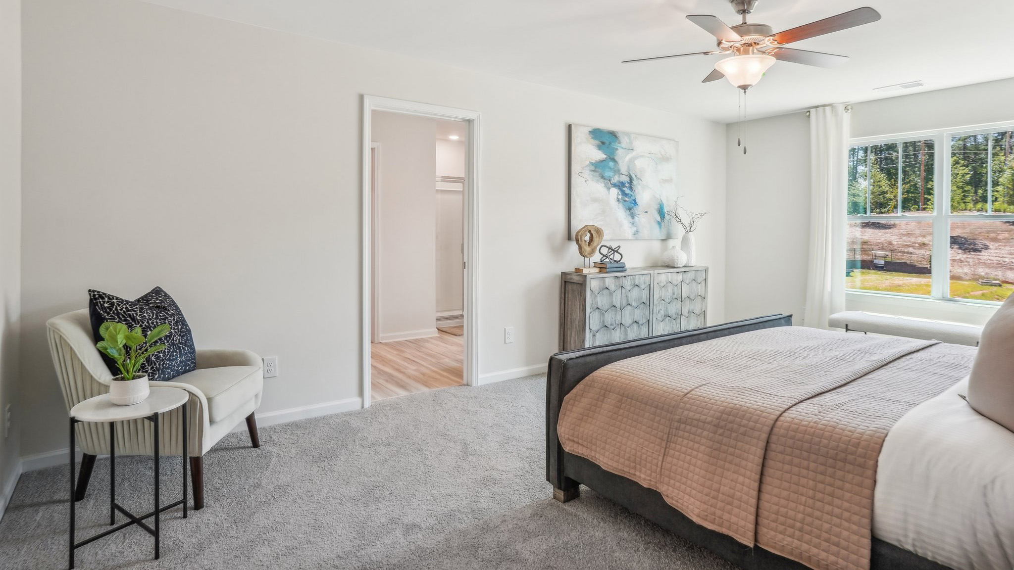 Model primary carpeted bedroom with large window