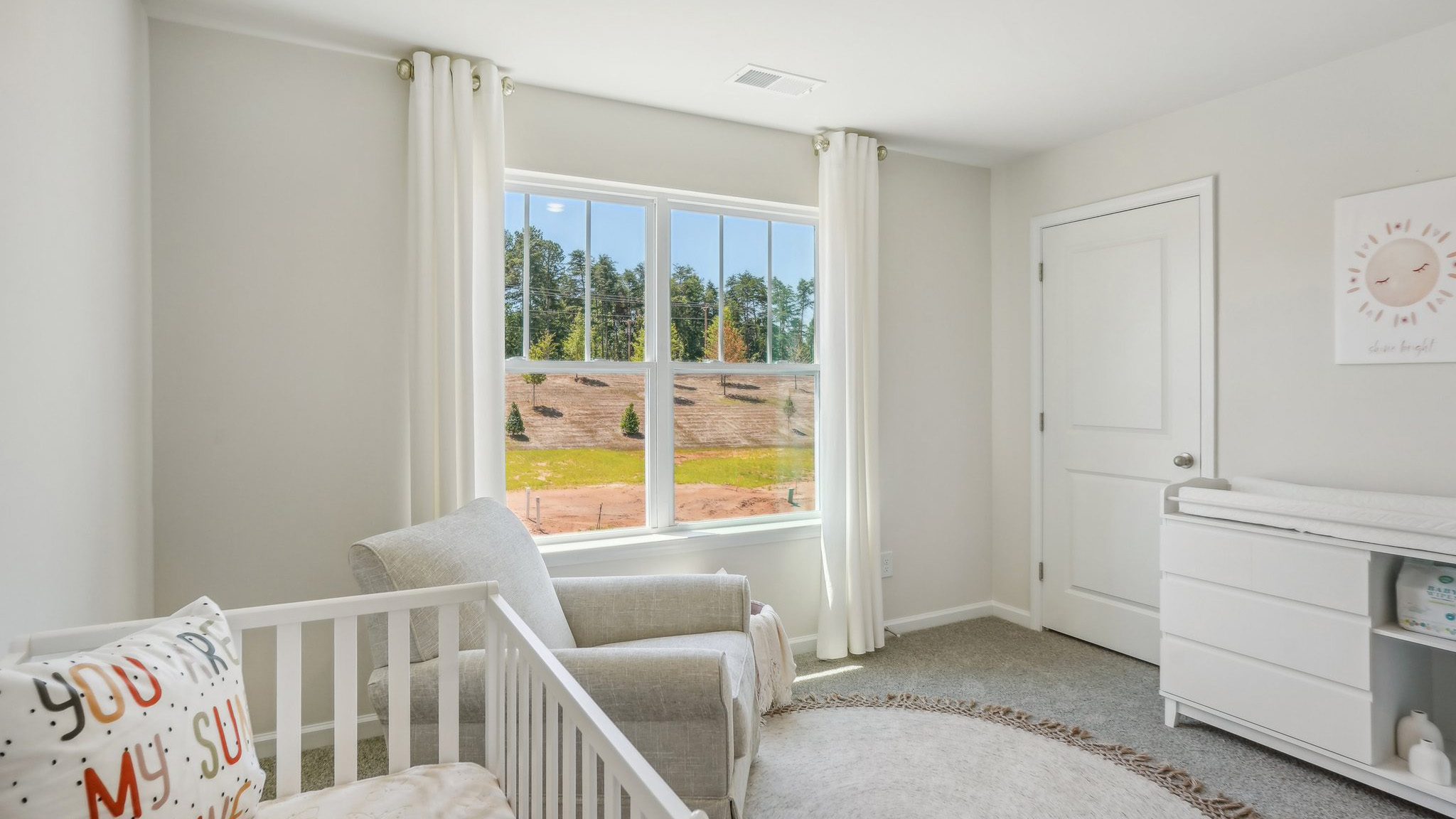 Model carpeted bedroom with large window