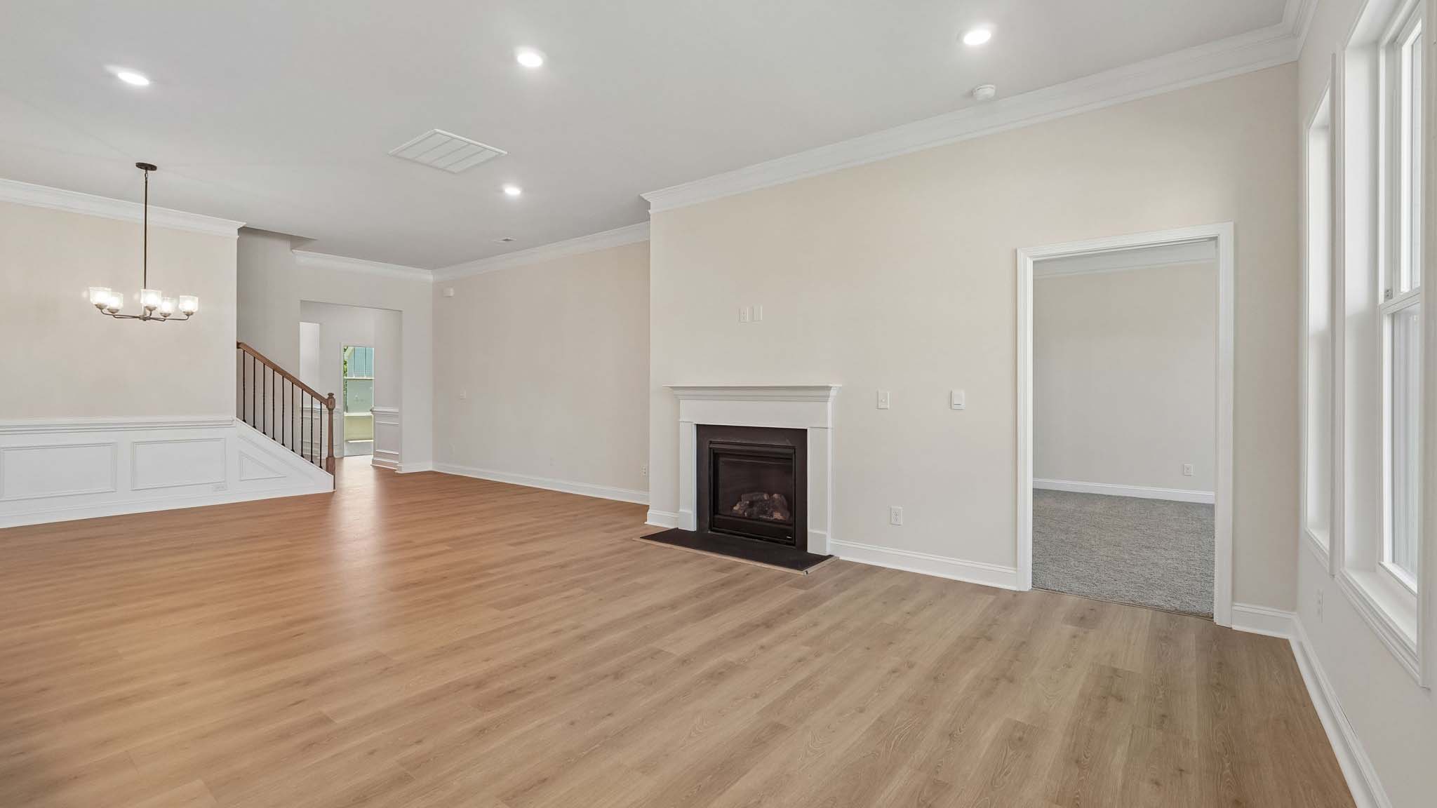 Open living room with wood floors, three windows, and fireplace