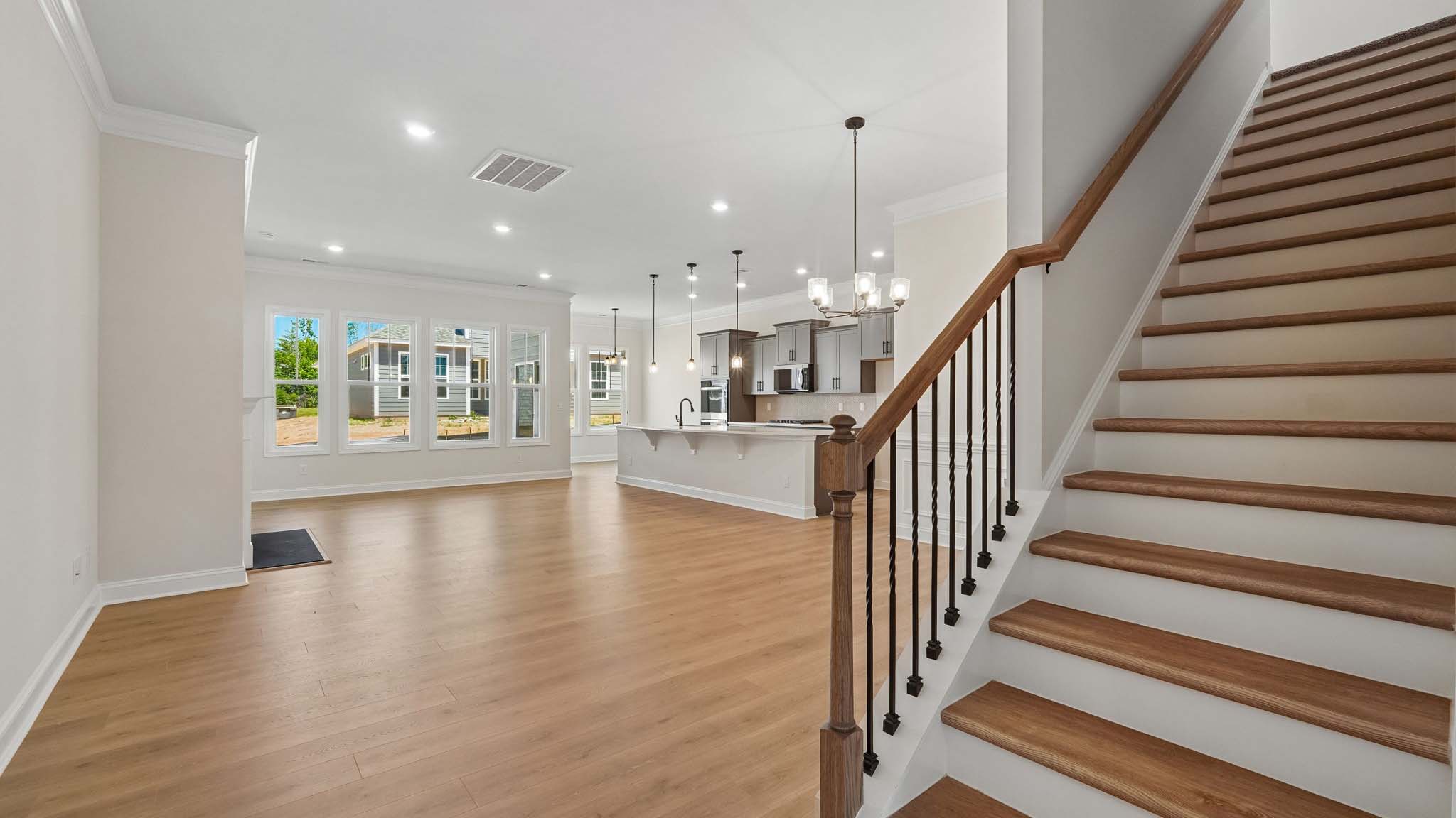Open living room with wood floors, three windows, and fireplace