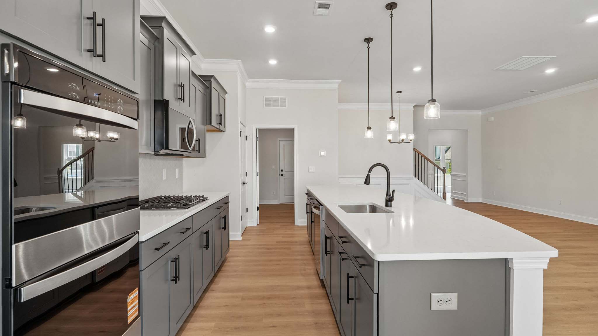 Kitchen and island with wood floors, white cabinets and counters, stainless steel appliances, and seating at island bar