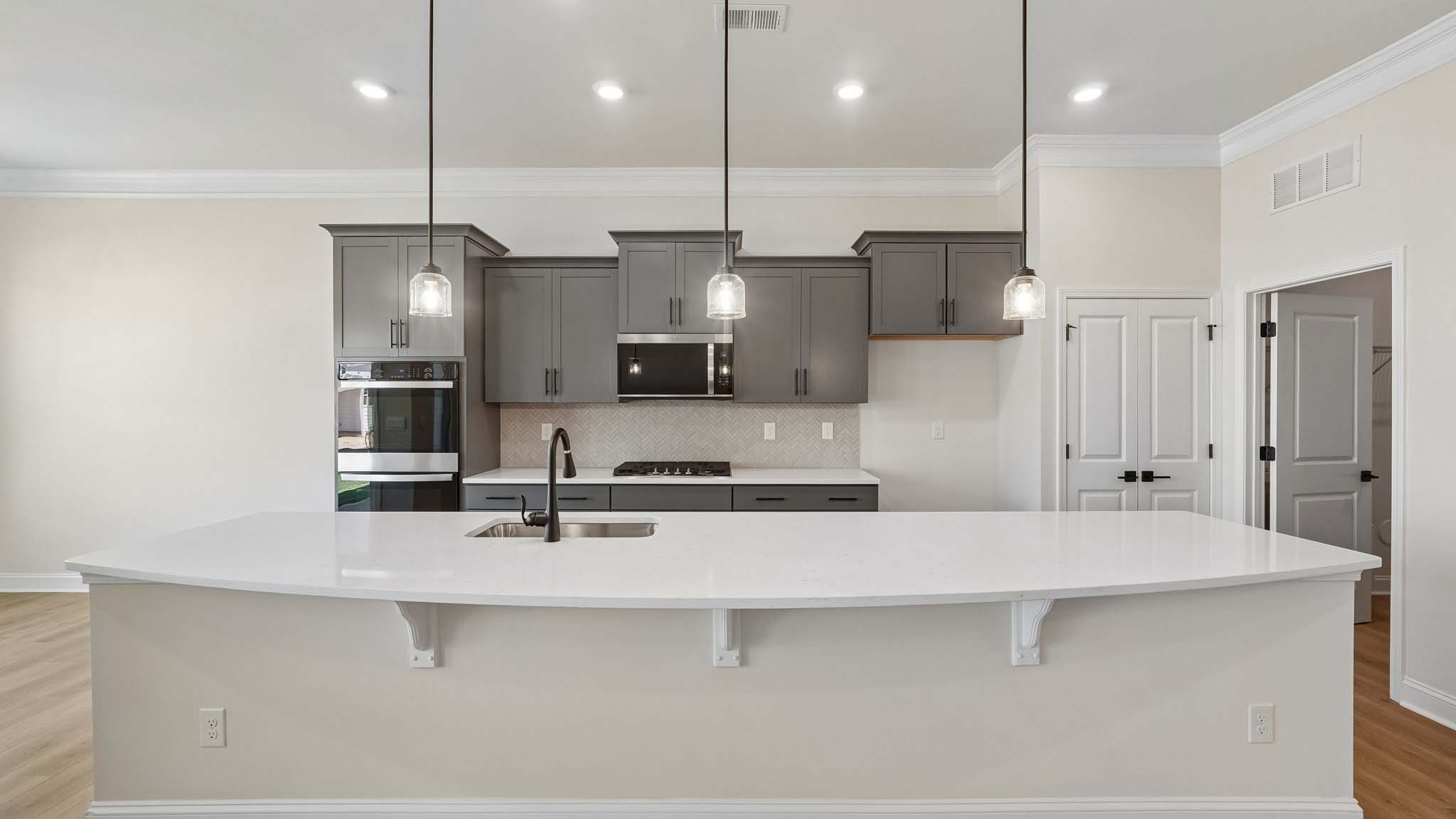 Kitchen and island with wood floors, white cabinets and counters, stainless steel appliances, and seating at island bar