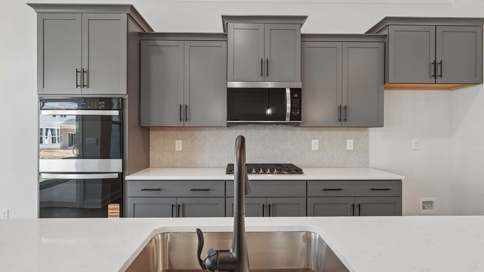 Kitchen and island with wood floors, white cabinets and counters, stainless steel appliances, and seating at island bar