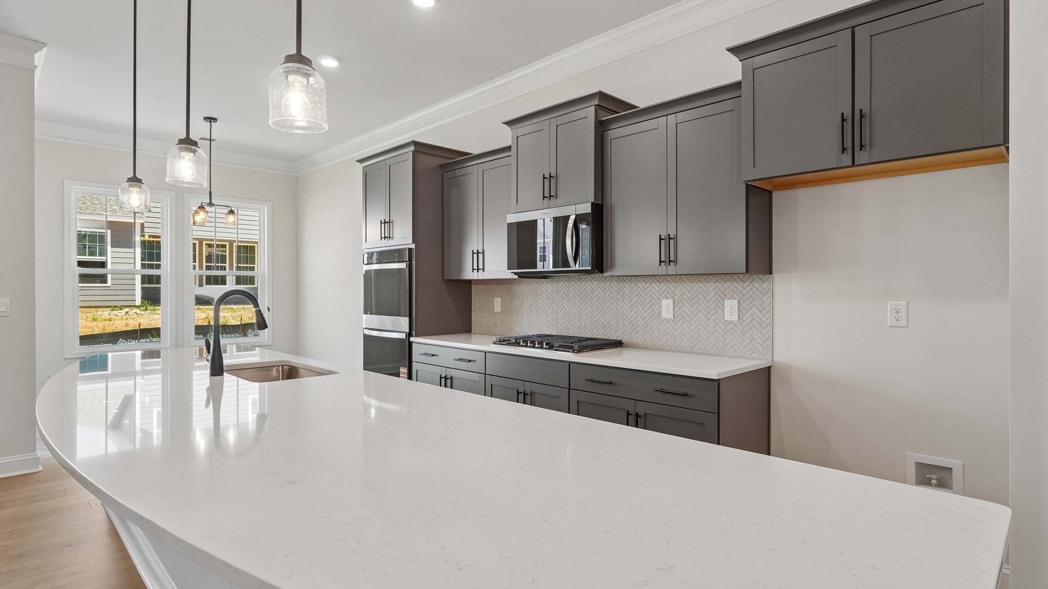Kitchen and island with wood floors, white cabinets and counters, stainless steel appliances, and seating at island bar