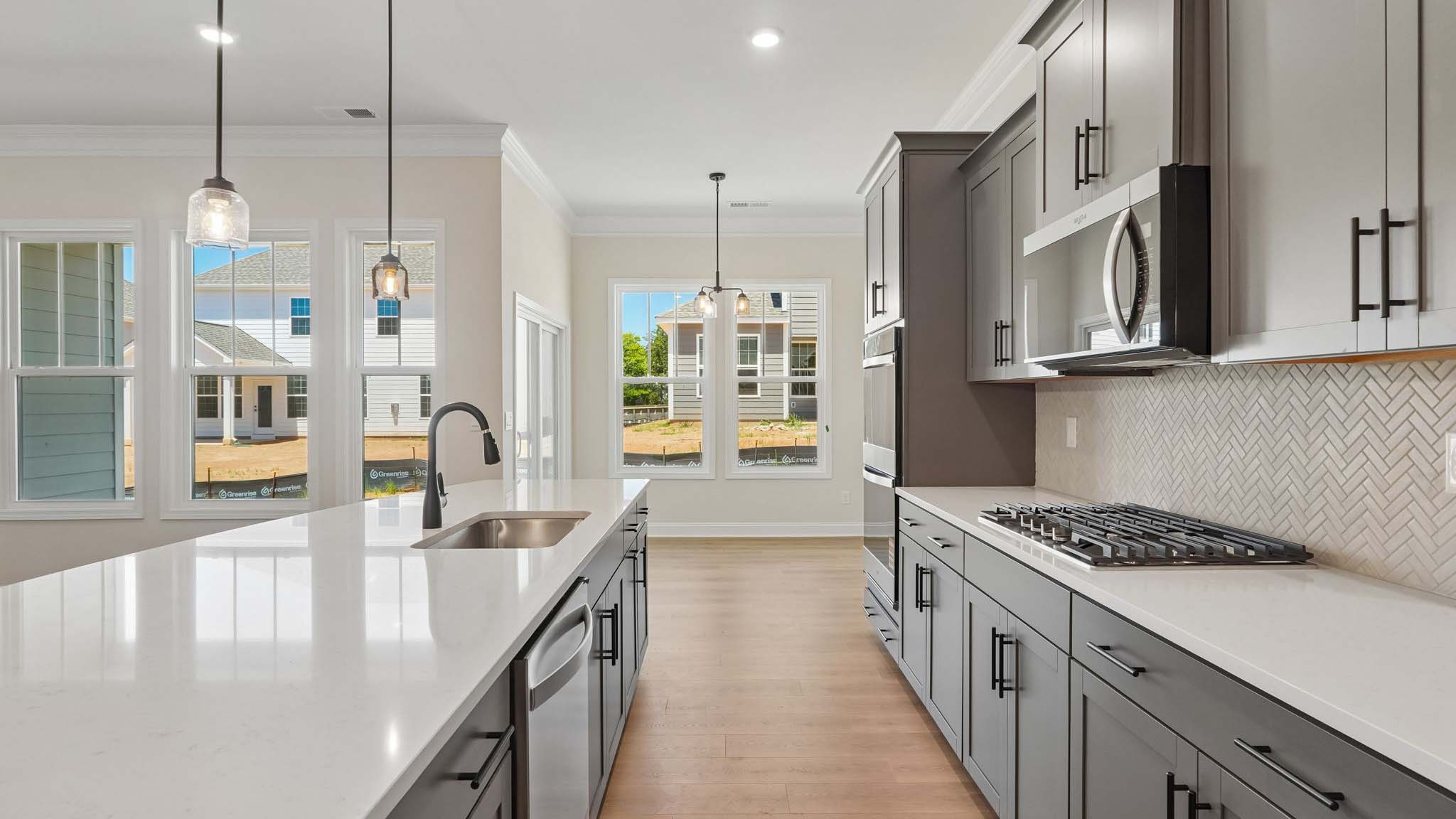 Kitchen and island with wood floors, white cabinets and counters, stainless steel appliances, and seating at island bar