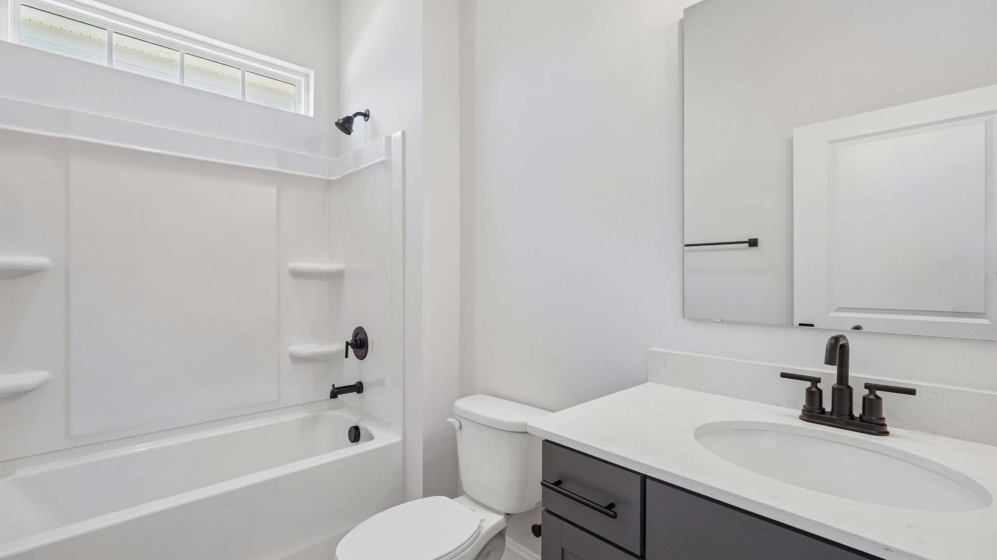Bathroom with bathtub, white cabinets and counters