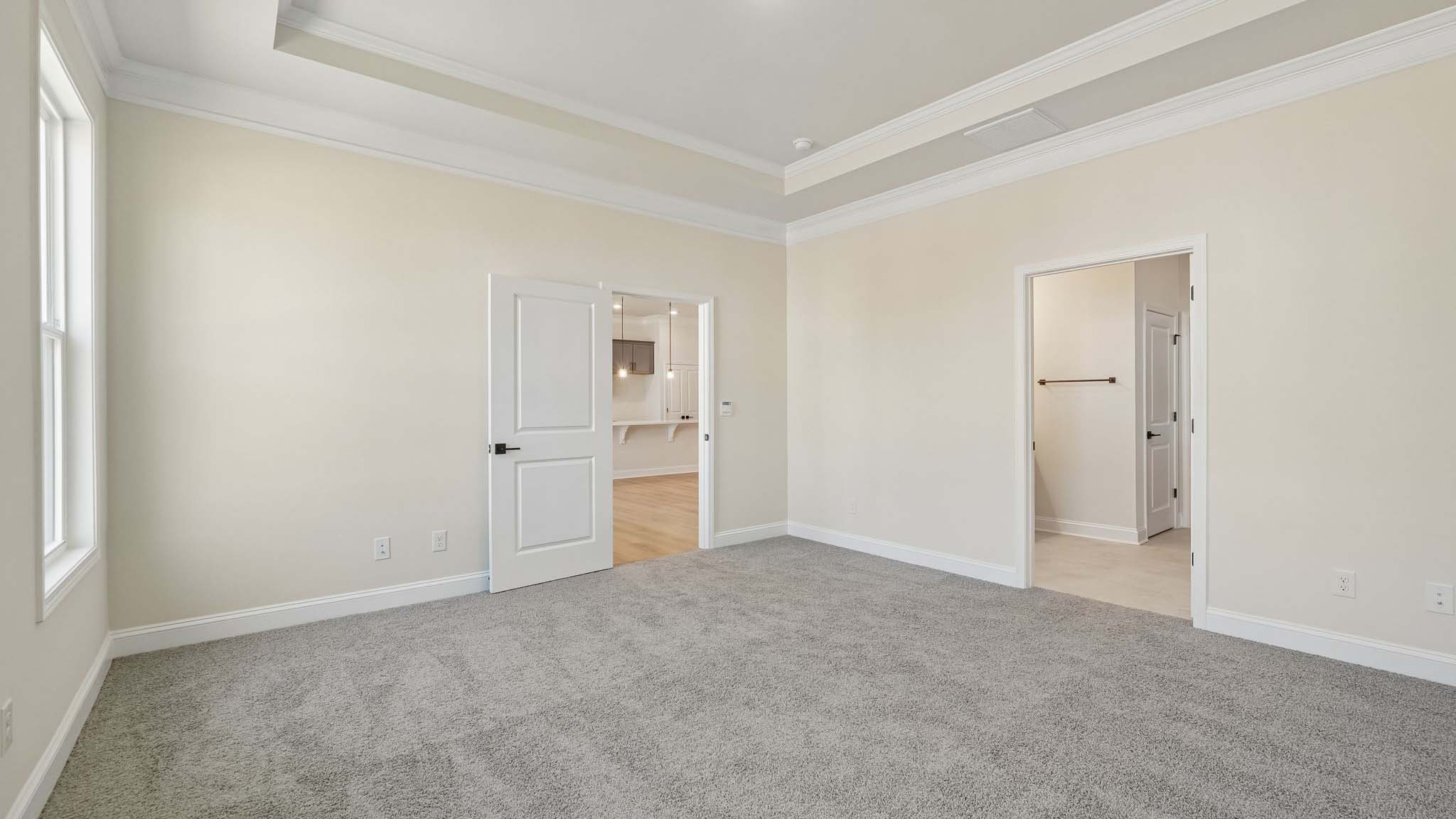 Primary bedroom with wood floors, and two large windows