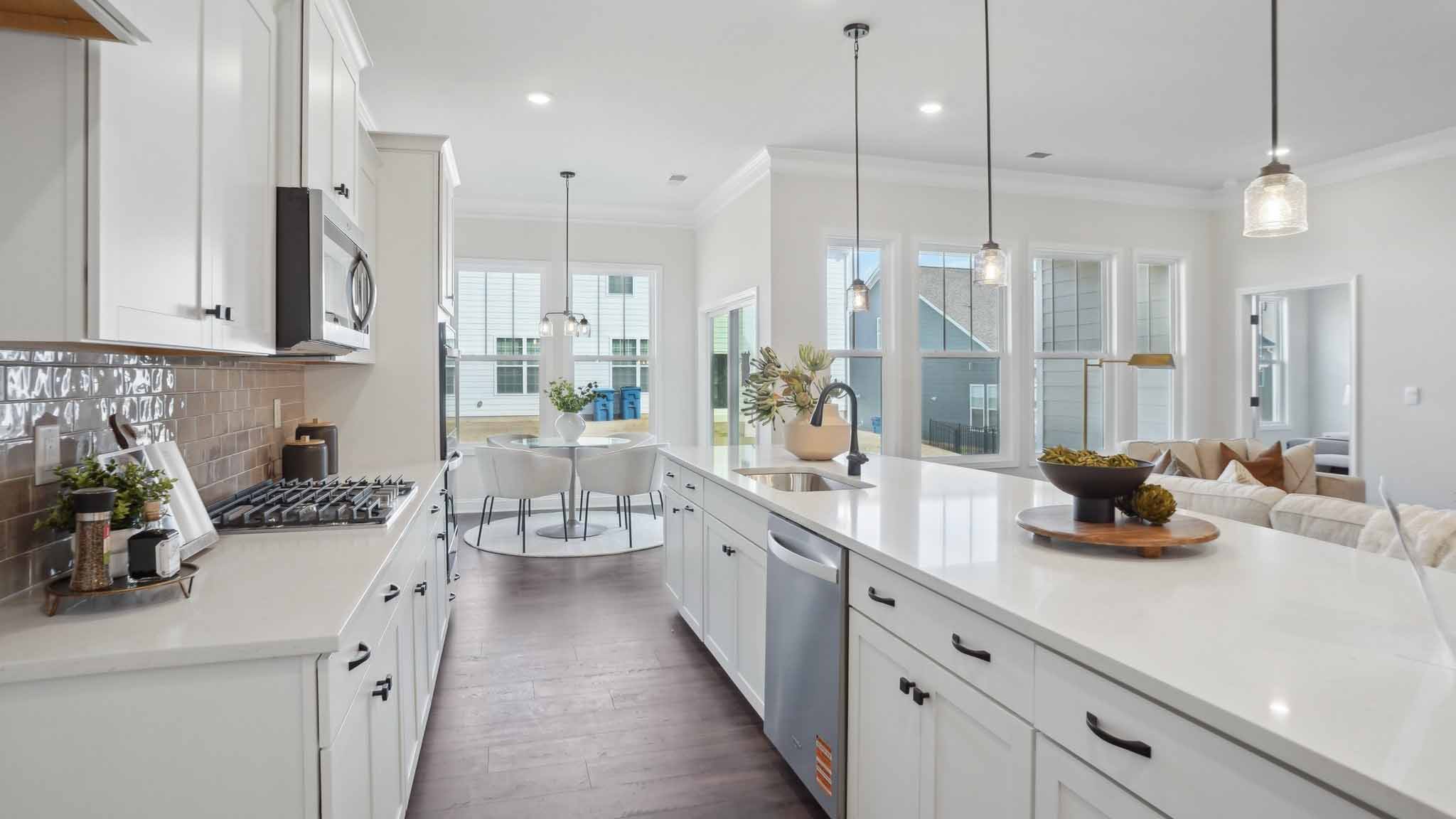 Kitchen and island with wood floors, white cabinets and counters, stainless steel appliances, and seating at island bar