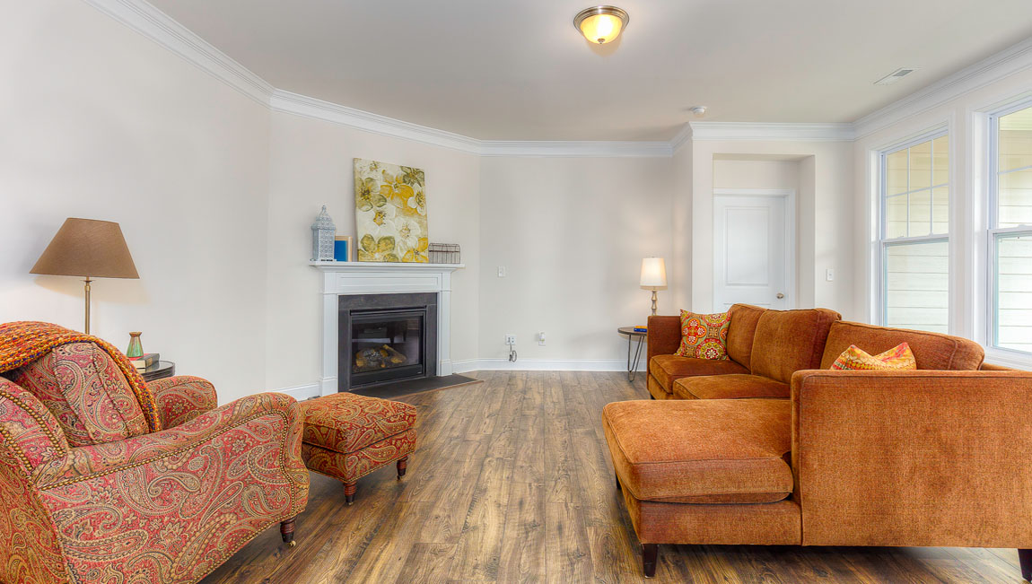 Open concept family room with wood floors, 3 large windows, and fireplace