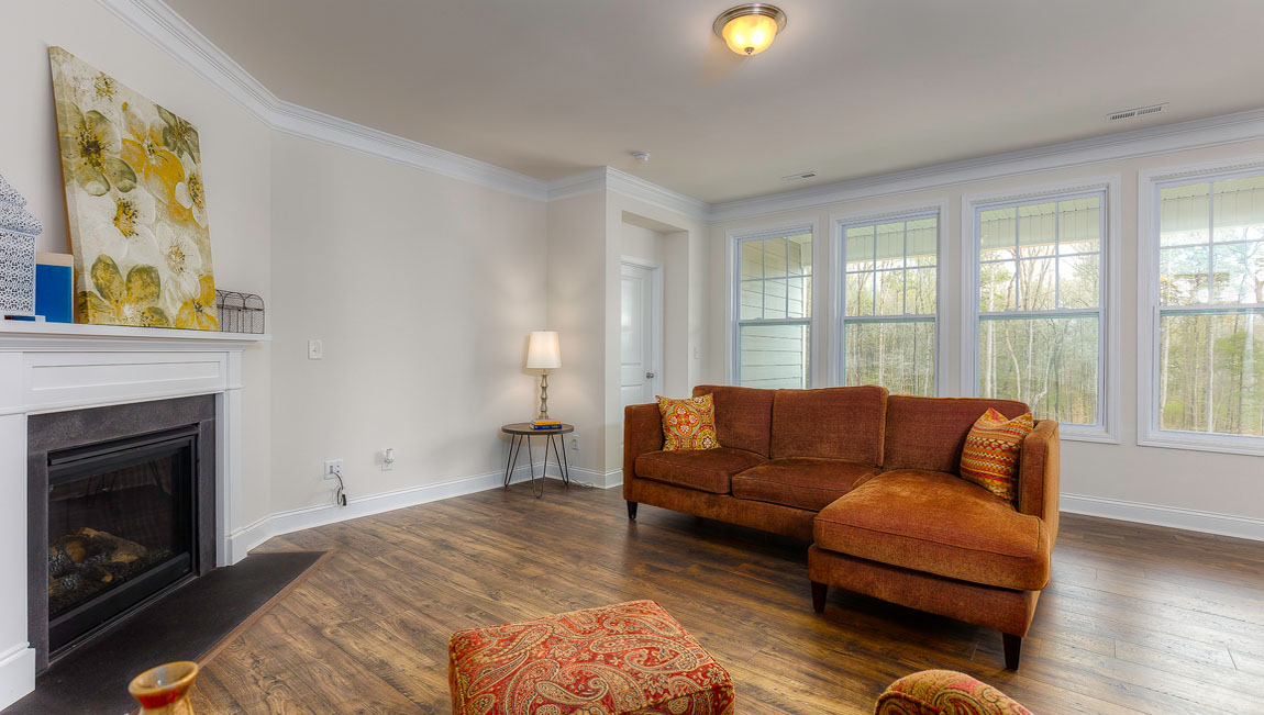 Open concept family room with wood floors, 3 large windows, and fireplace