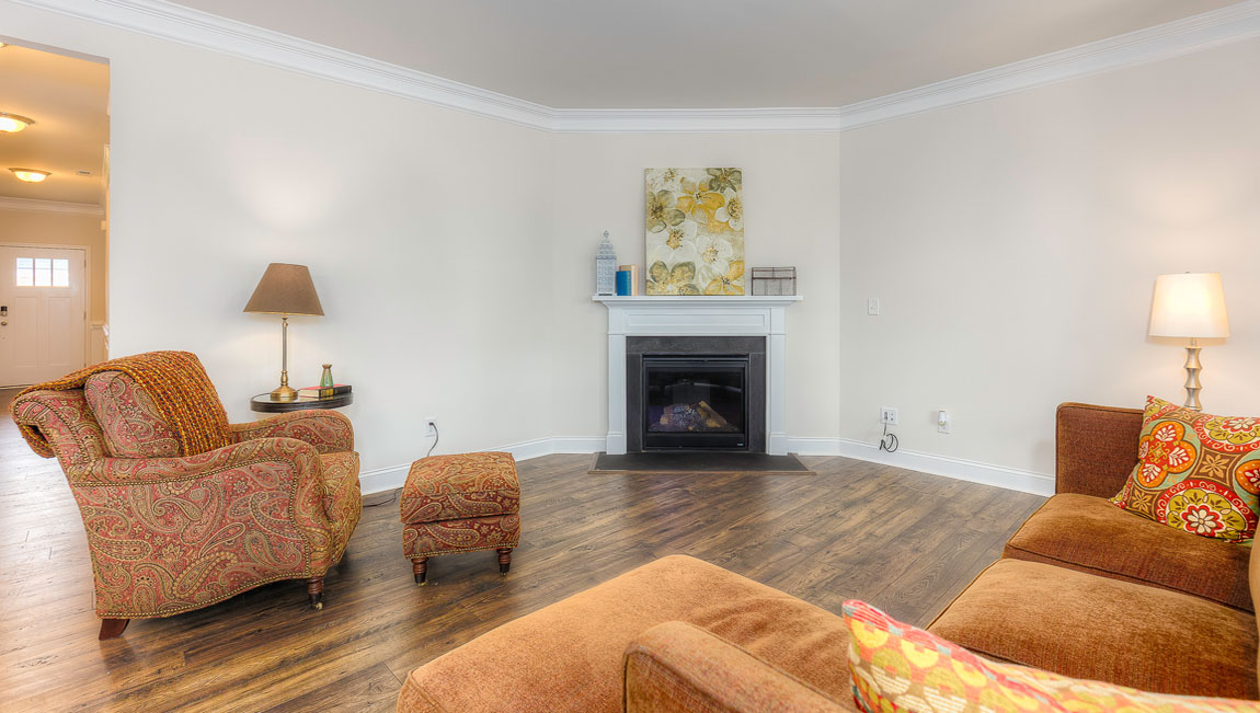 Open concept family room with wood floors, 3 large windows, and fireplace