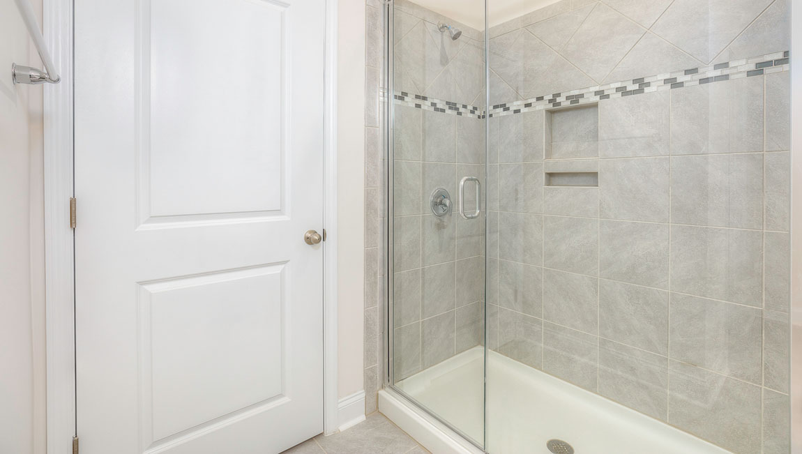 Primary bathroom with two sinks and counters, white cabinets, and wood floors