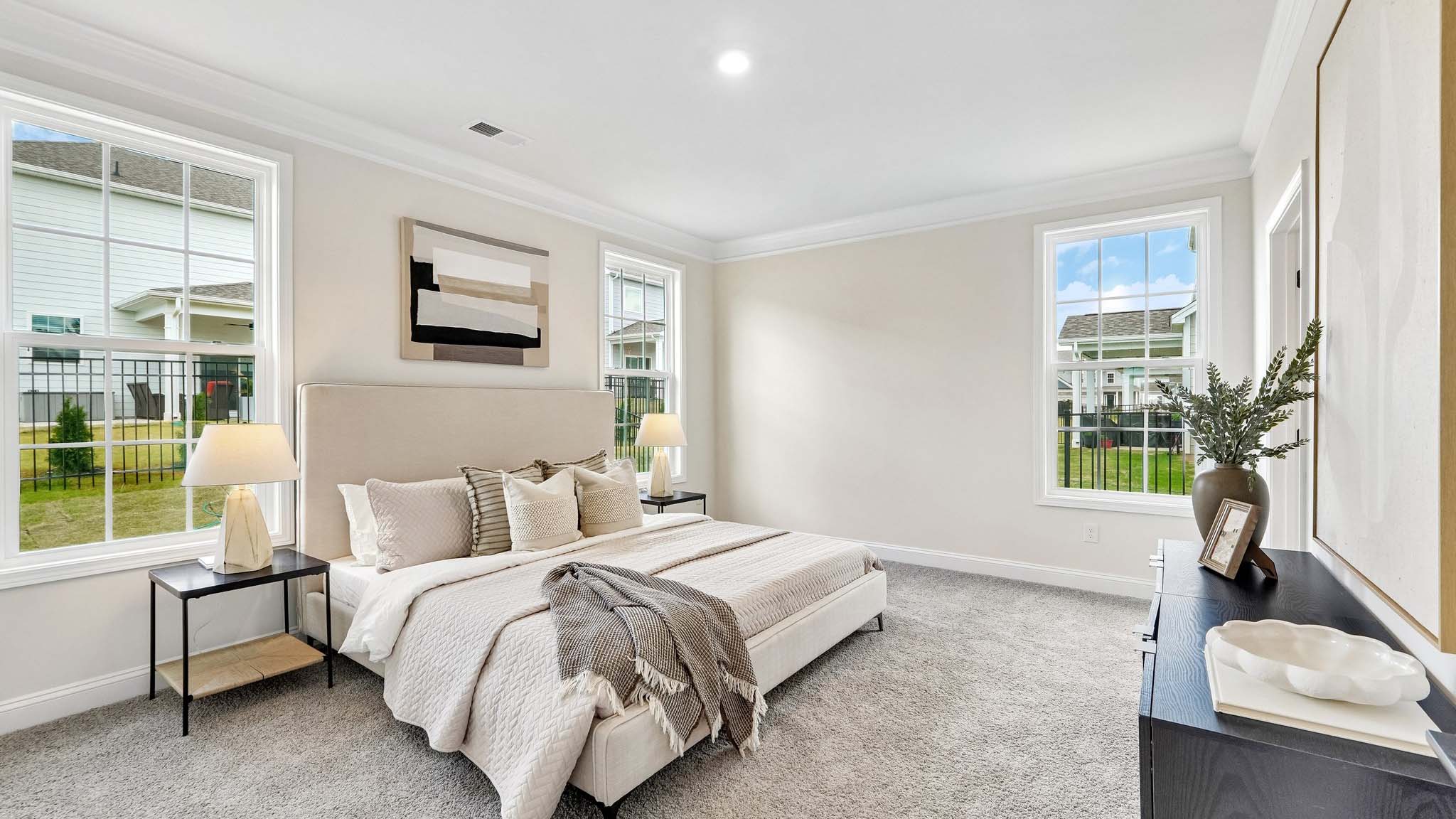 Primary carpeted bedroom with large windows