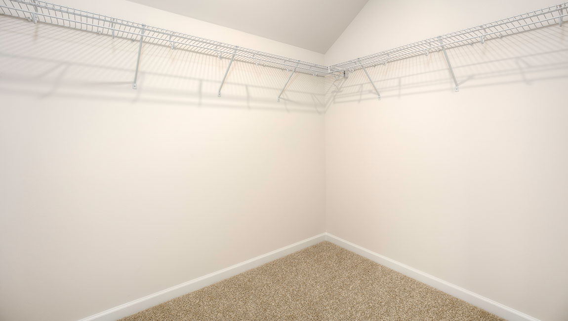 Carpeted walk in closet with built in hanger racks