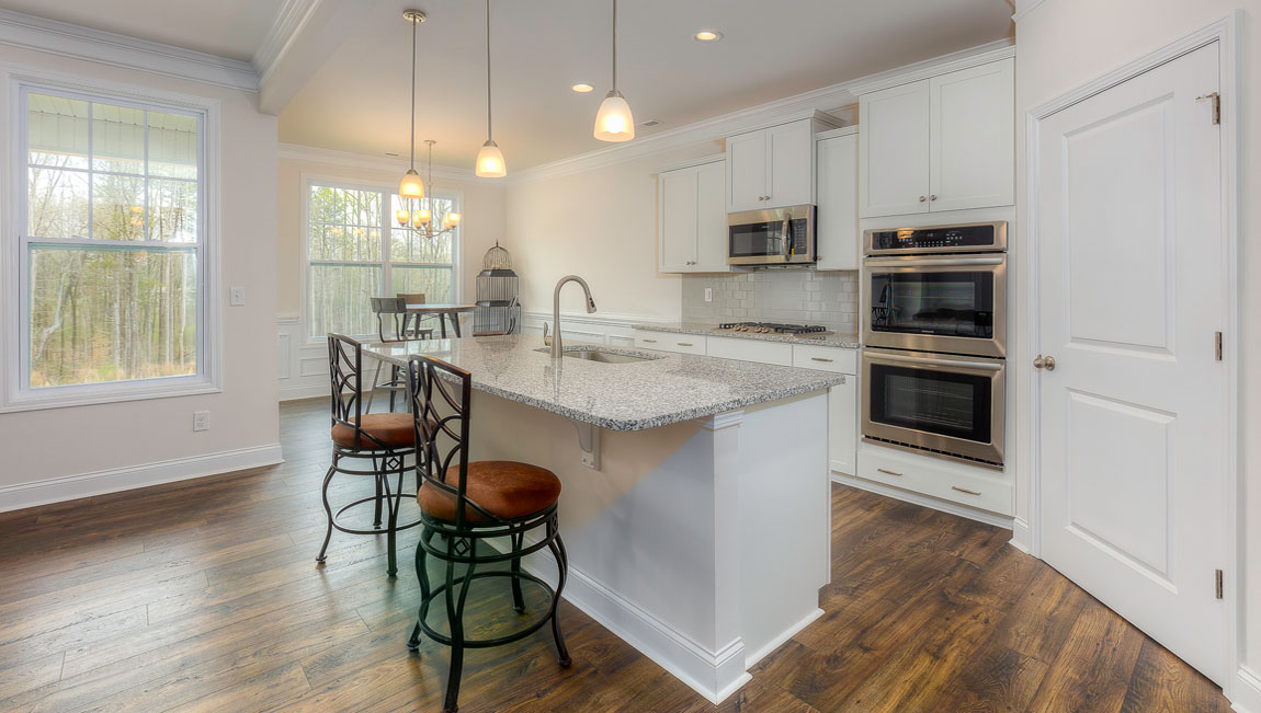 Kitchen and island with wood floors, white cabinets, quartz counters, and stainless steel appliances