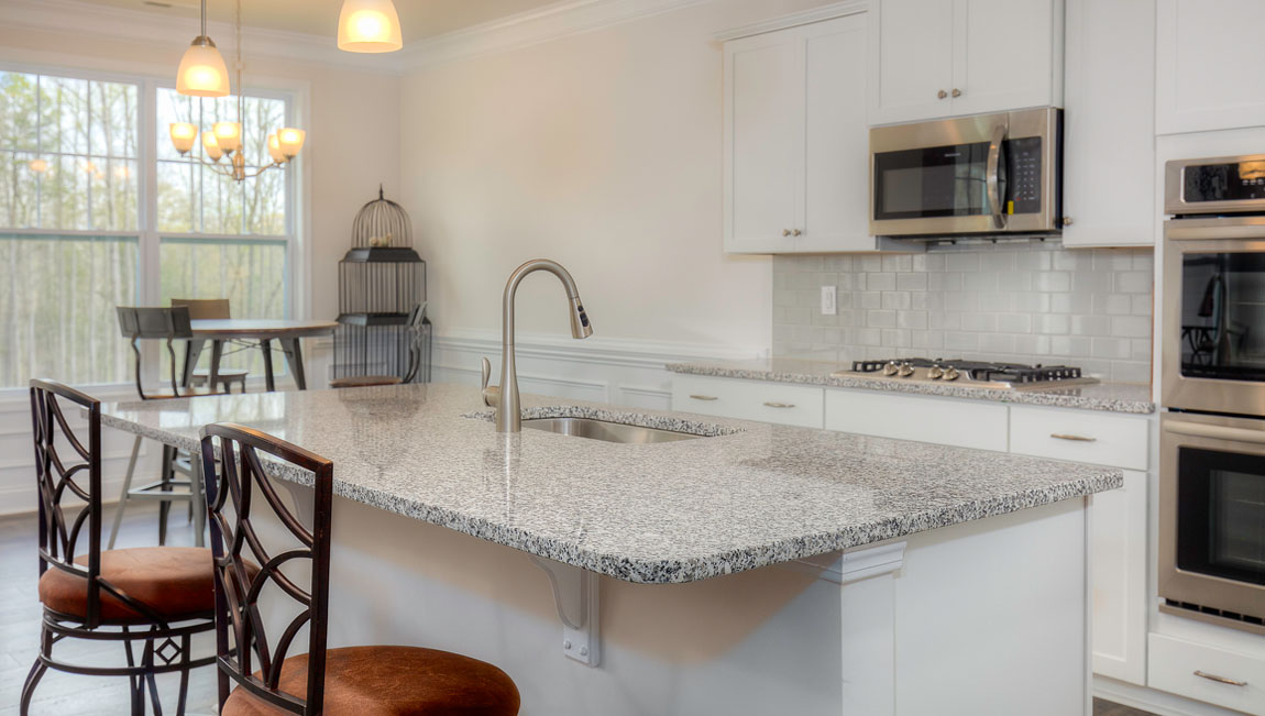 Kitchen and island with wood floors, white cabinets, quartz counters, and stainless steel appliances