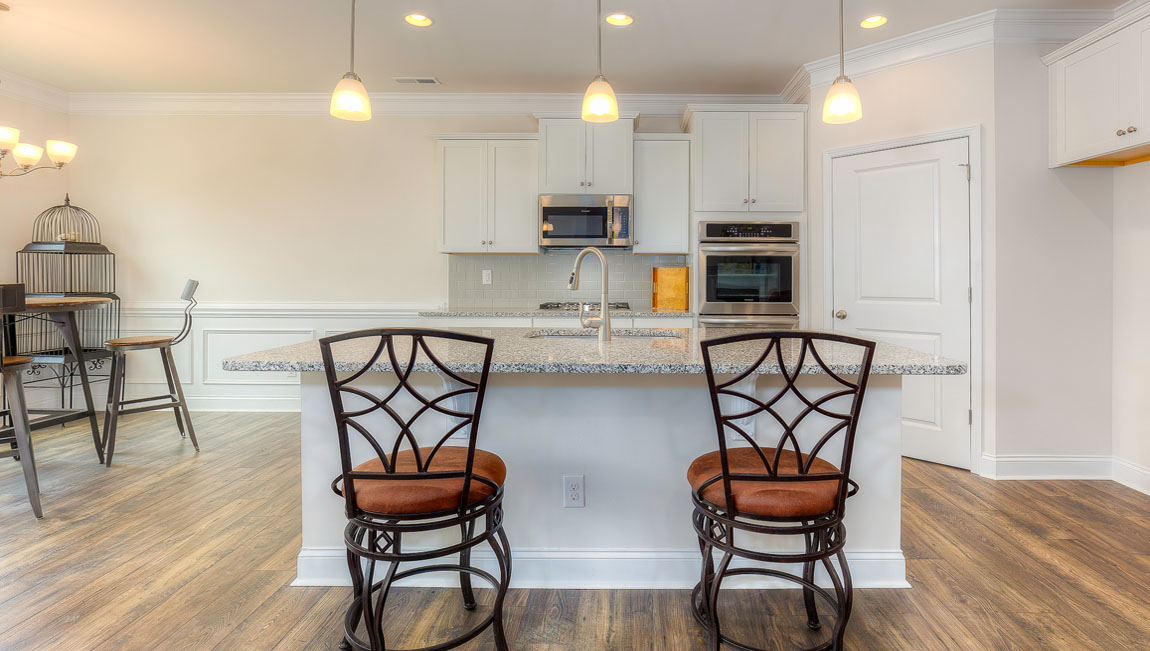Kitchen and island with wood floors, white cabinets, quartz counters, and stainless steel appliances