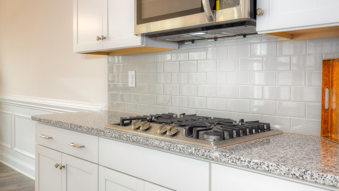 Kitchen and island with wood floors, white cabinets, quartz counters, and stainless steel appliances