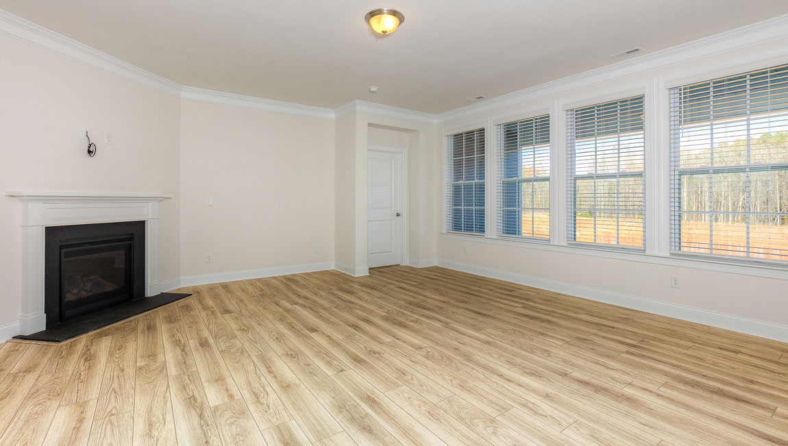 Open concept family room with wood floors, 3 large windows, and fireplace